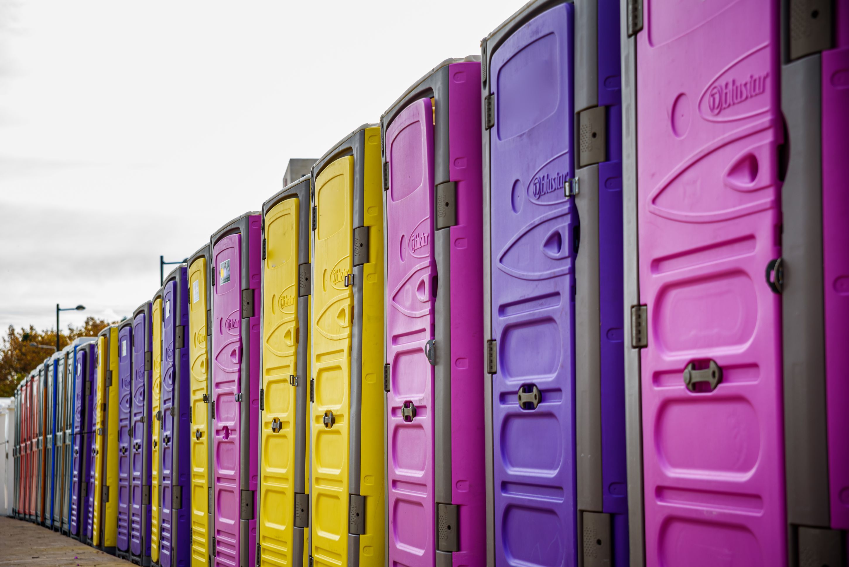 row-of-portable-chemical-toilets-of-various-colors-2024-10-21-09-02-52-utc